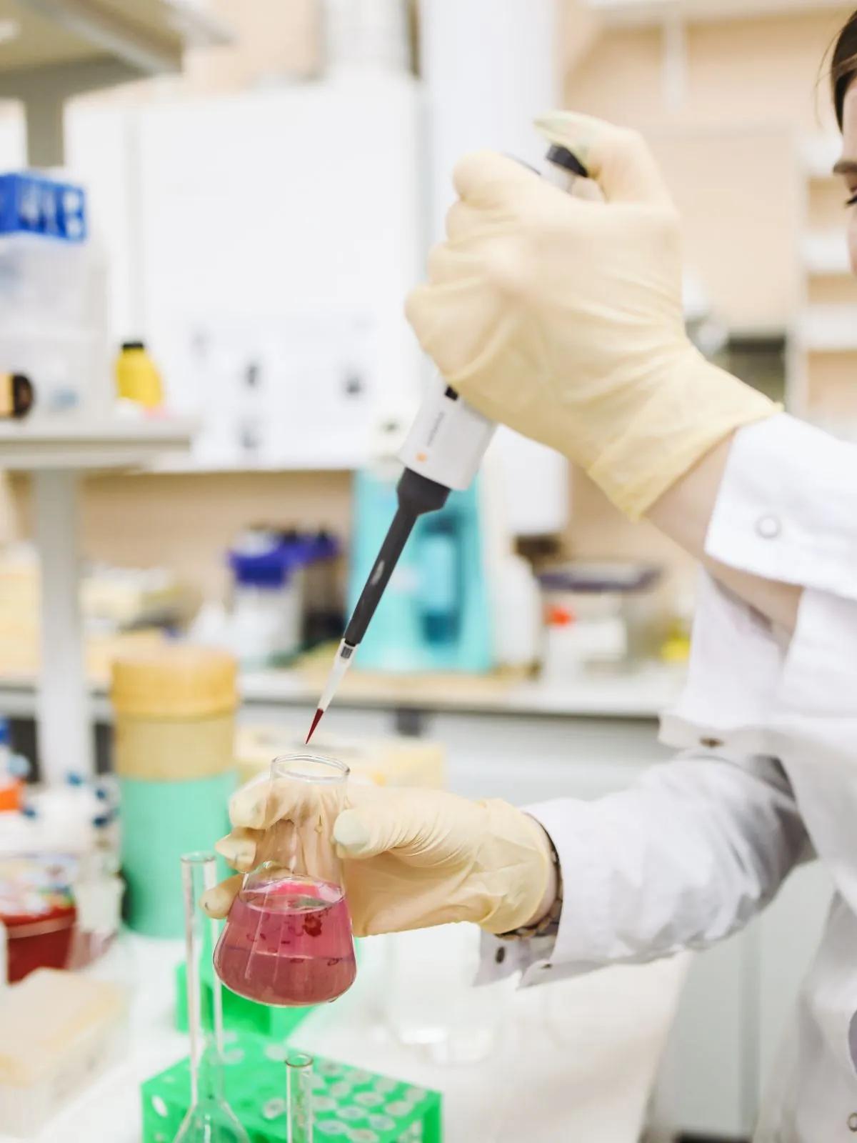 A scientist in a white coat pipetting samples at a laboratory bench