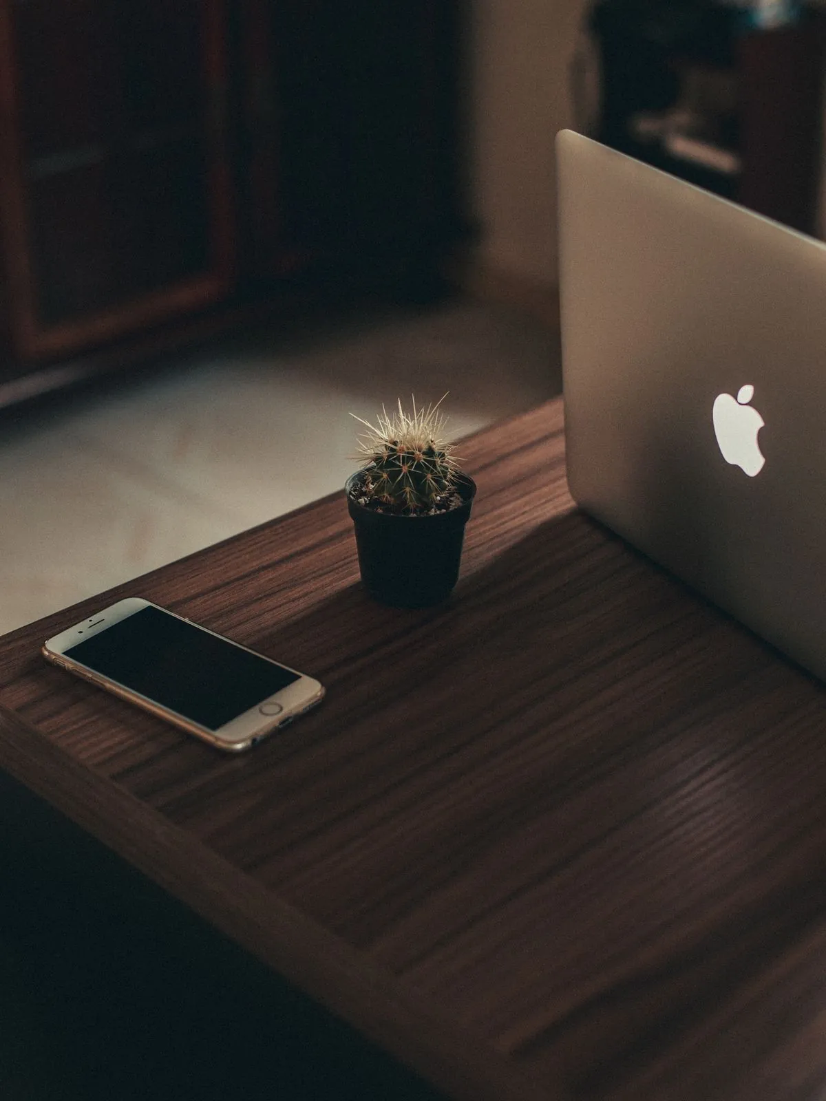 An iPhone and a MacBook on a dark wooden table