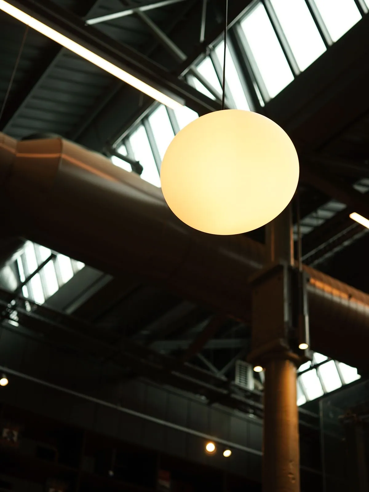 A pendant light fixture under an industrial ceiling